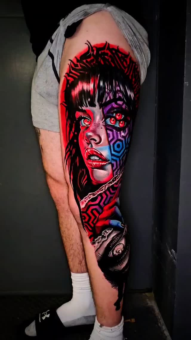 Tatouage portrait graphique rouge et bleu avec multiples yeux et motifs géométriques